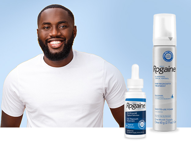 Man in white t-shirt smiling on a light blue background with two bottles of Rogaine Solution.